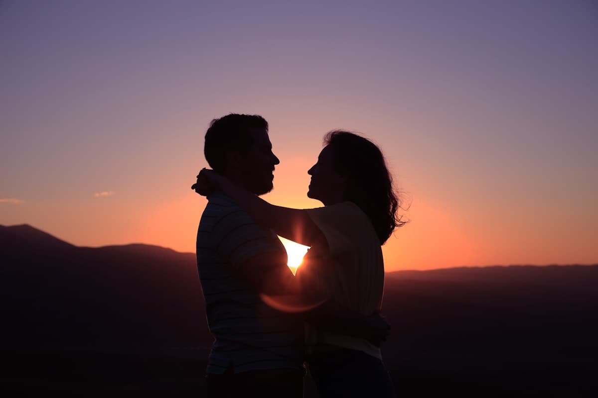 Paar umarmt sich vor Sonnenuntergang in den Bergen